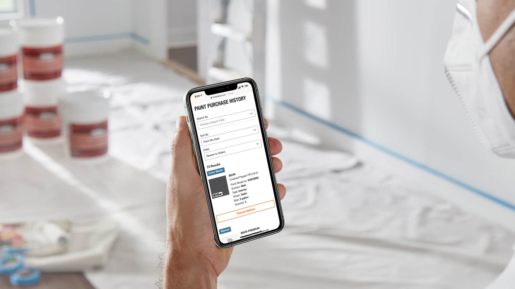 Home Depot paint purchase history displayed on a phone held above a painting workspace
